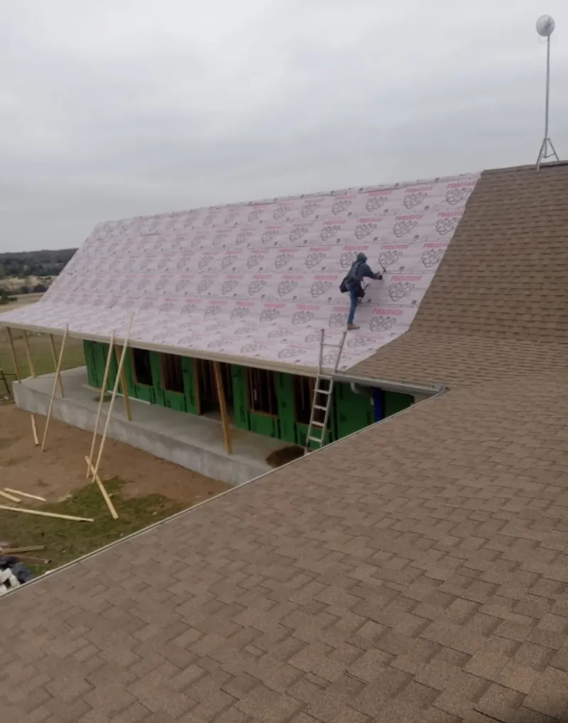 Worker preparing underlayment for a metal roof installation in Straban